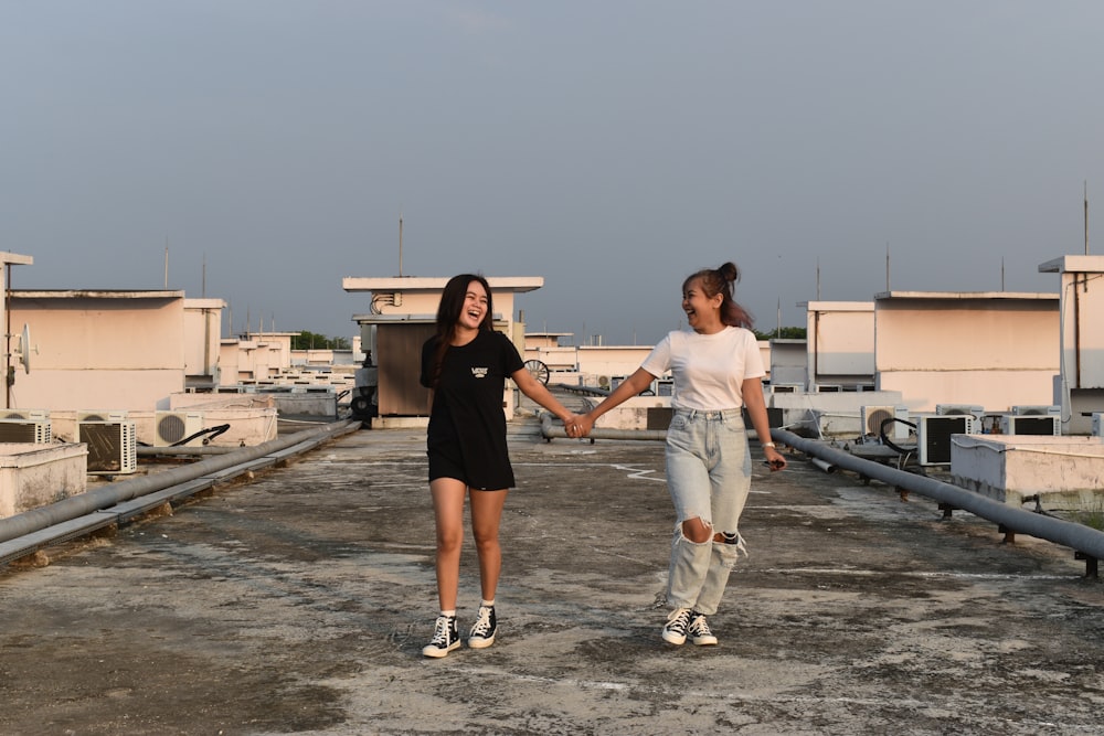 two women holding hands on a roof of a building
