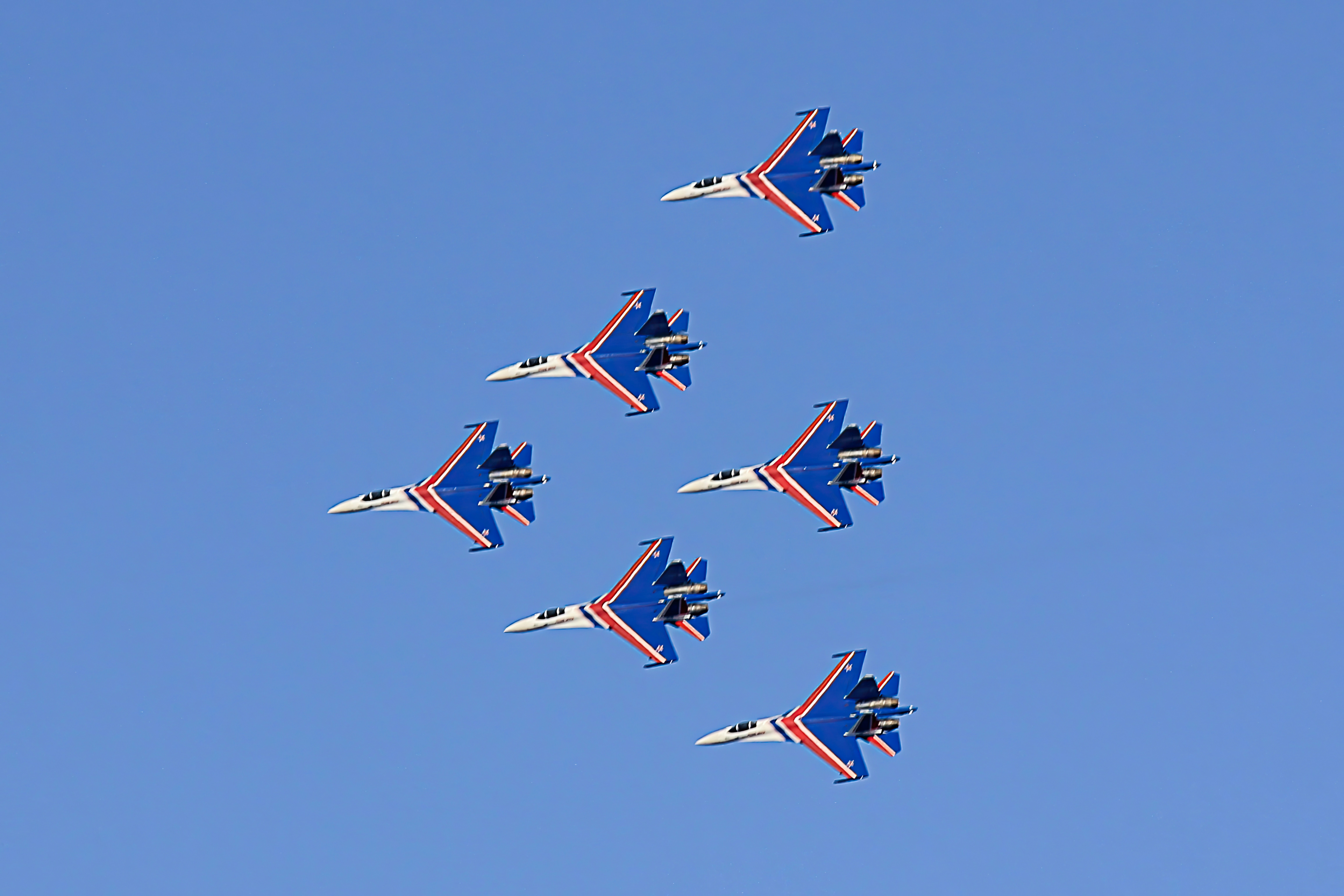 a group of fighter jets flying through a blue sky