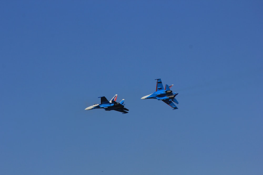 two fighter jets flying through a blue sky