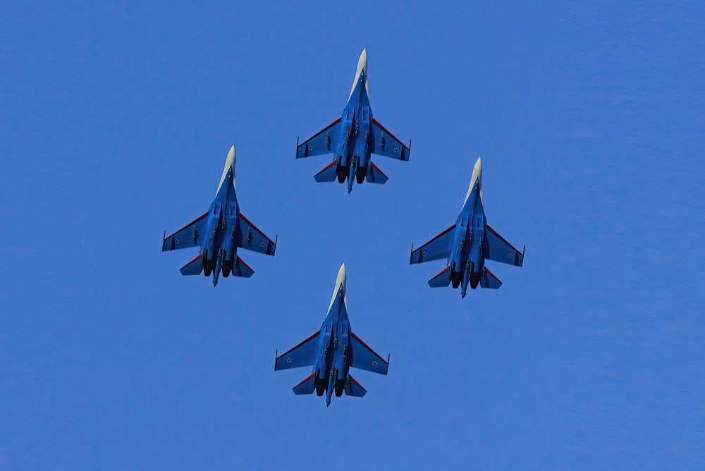 four fighter jets flying in formation in a blue sky