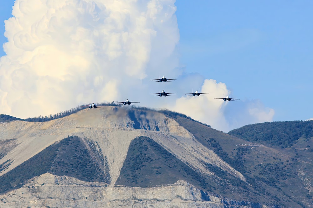 a group of fighter jets flying over a mountain