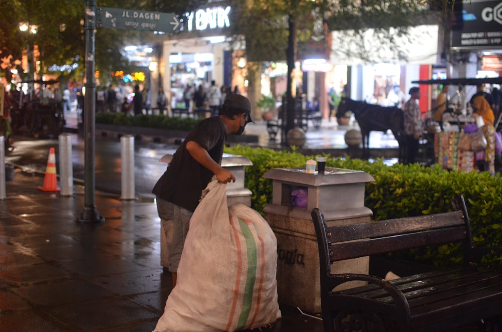 a man unloading a bag of garbage on a city street