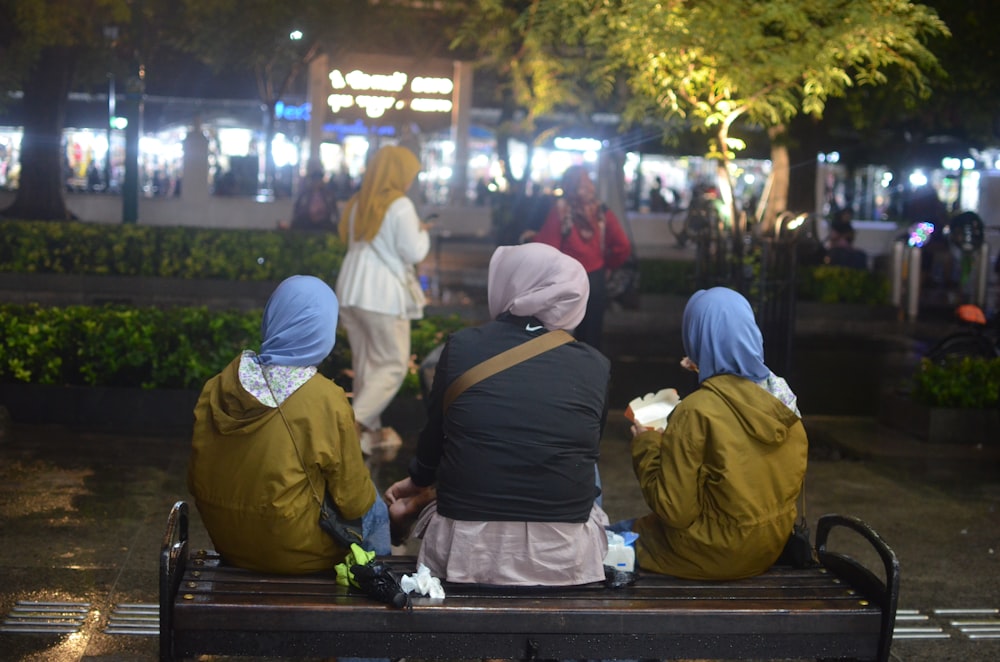 three women sitting on a bench at night