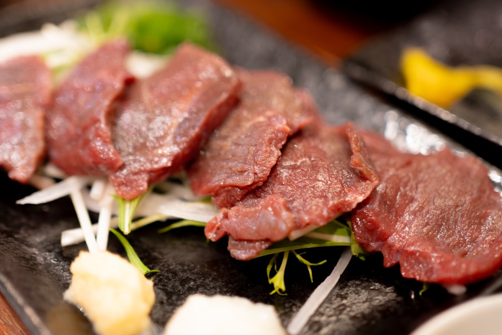 a black plate topped with slices of meat