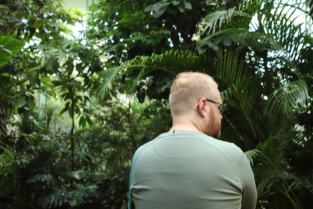 a man standing in front of a lush green forest