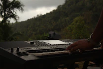 a person typing on a keyboard in front of a mountain