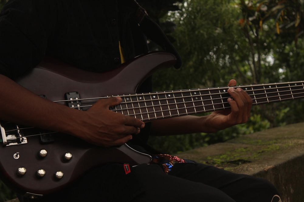 a man playing a bass guitar in a park