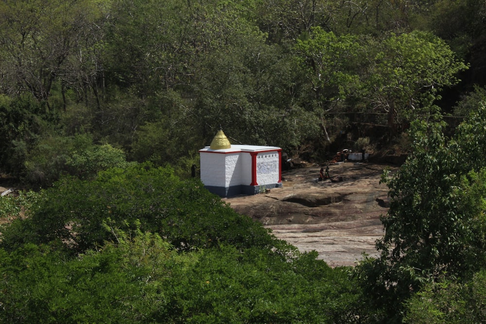 a small white and red building surrounded by trees