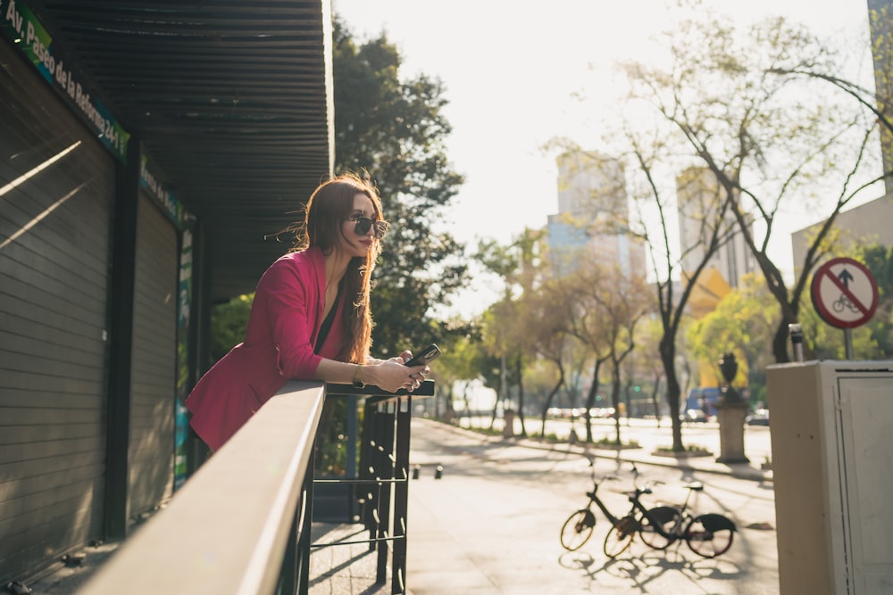 a woman leaning on a rail looking at her cell phone