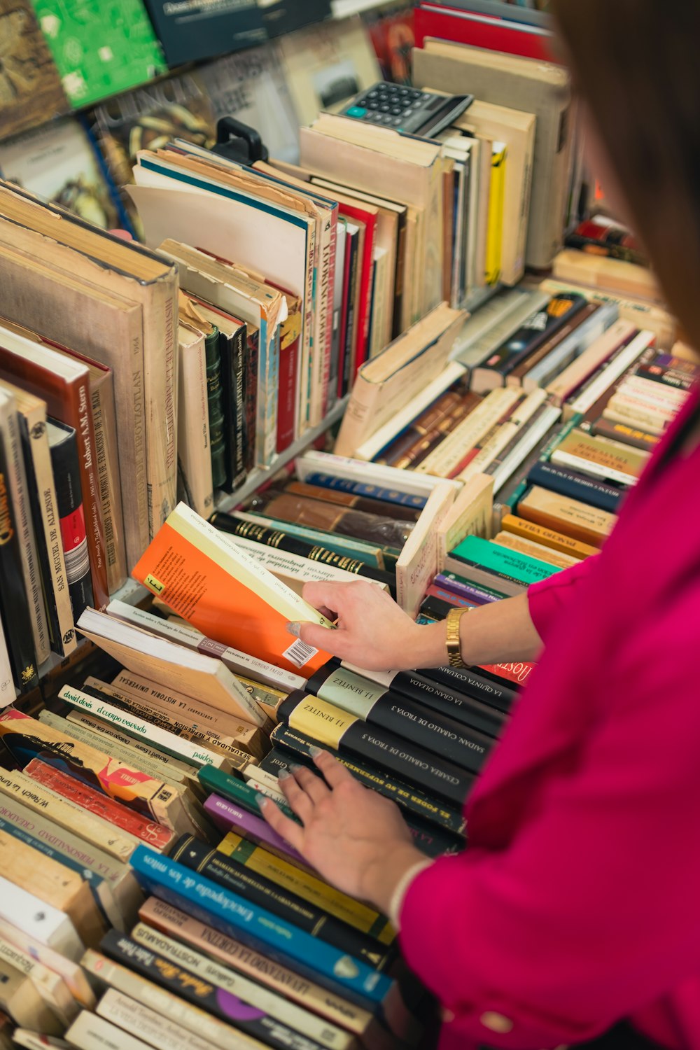 a woman is picking up a book from a bookcase