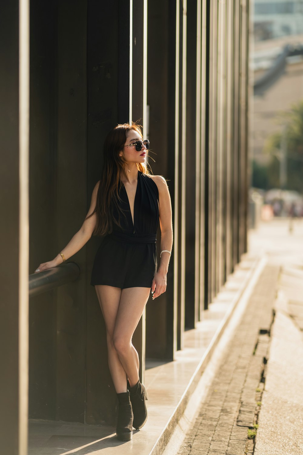 a woman in a short black dress leaning against a wall