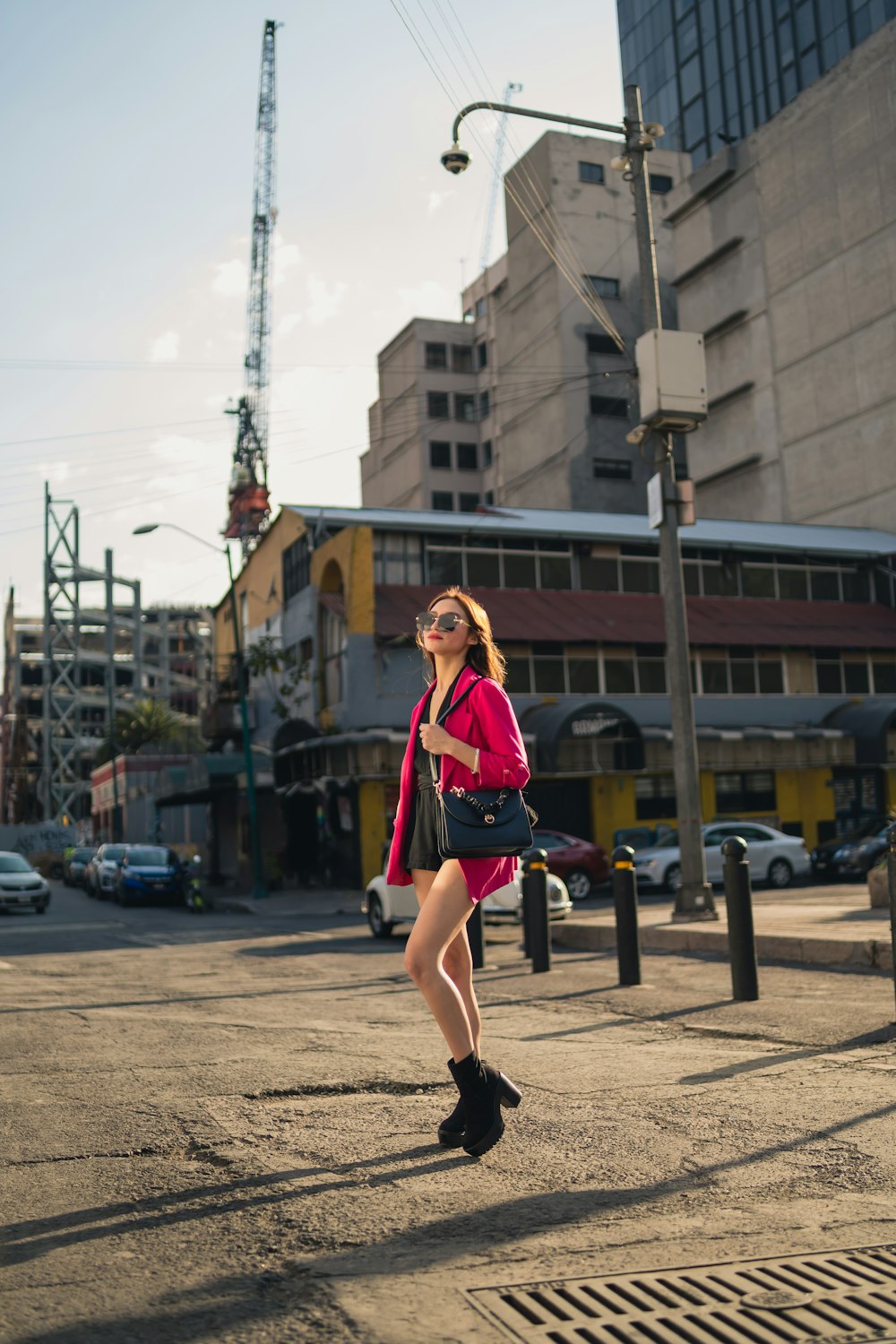 a woman walking down a street next to tall buildings