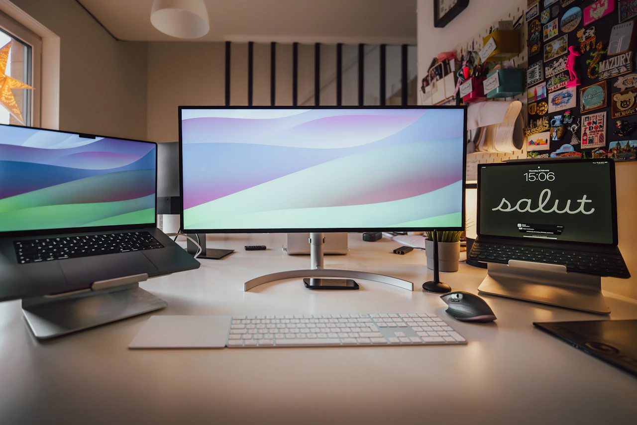 Organized desk with laptop, monitor and tablet used for digital publishing work.