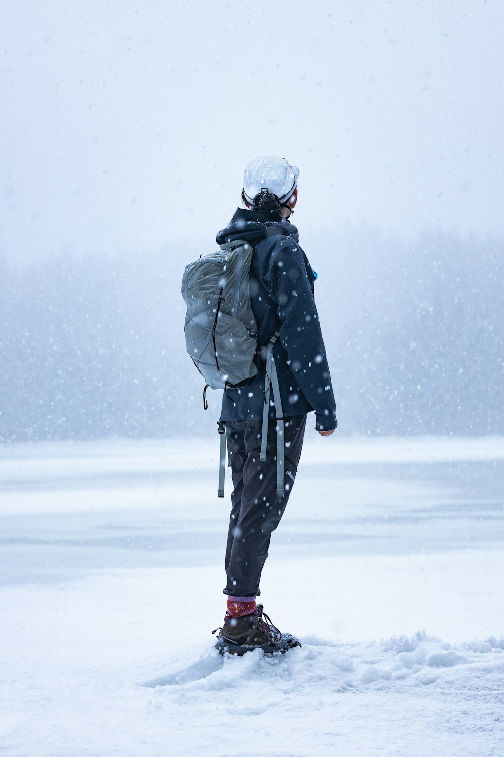 uma pessoa com uma mochila em pé na neve