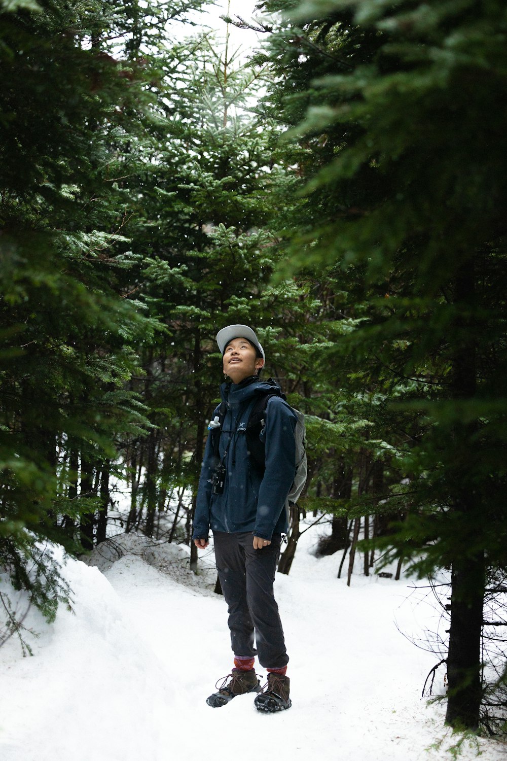 a man standing in the snow in front of some trees