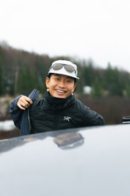 a man wearing a hat and goggles standing next to a car
