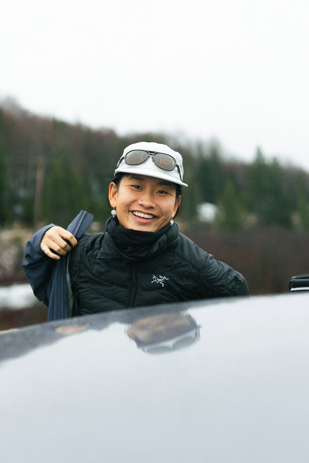 a man wearing a hat and goggles standing next to a car