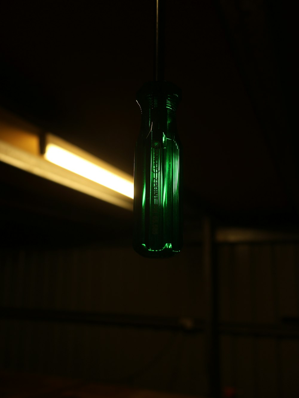 a green glass bottle hanging from a ceiling