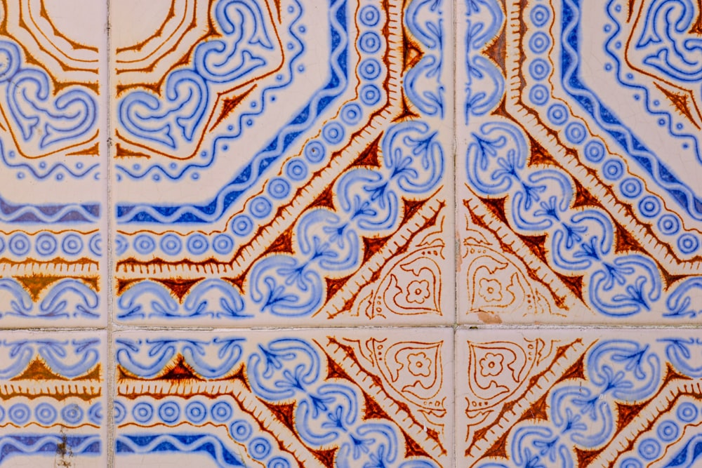 um close up de uma parede de azulejos com desenhos azuis e laranjas