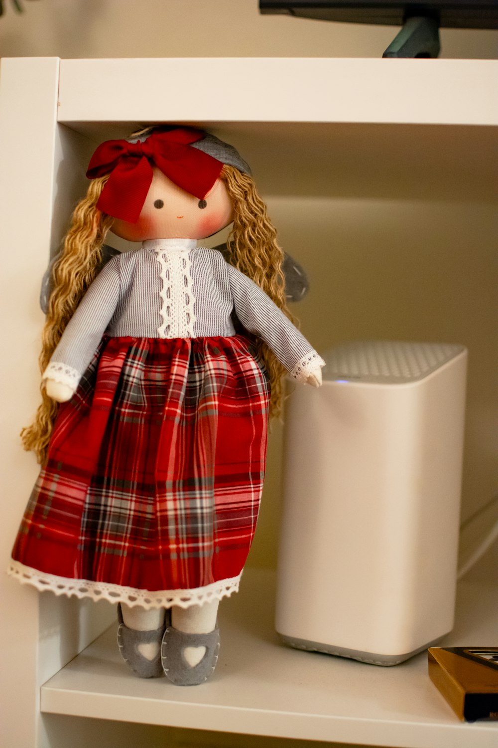 a doll is sitting on a shelf next to a trash can