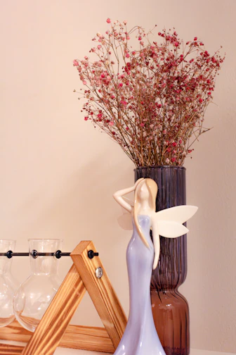 a vase with flowers and a fairy figurine