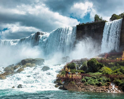 a large waterfall with people standing on the side of it
