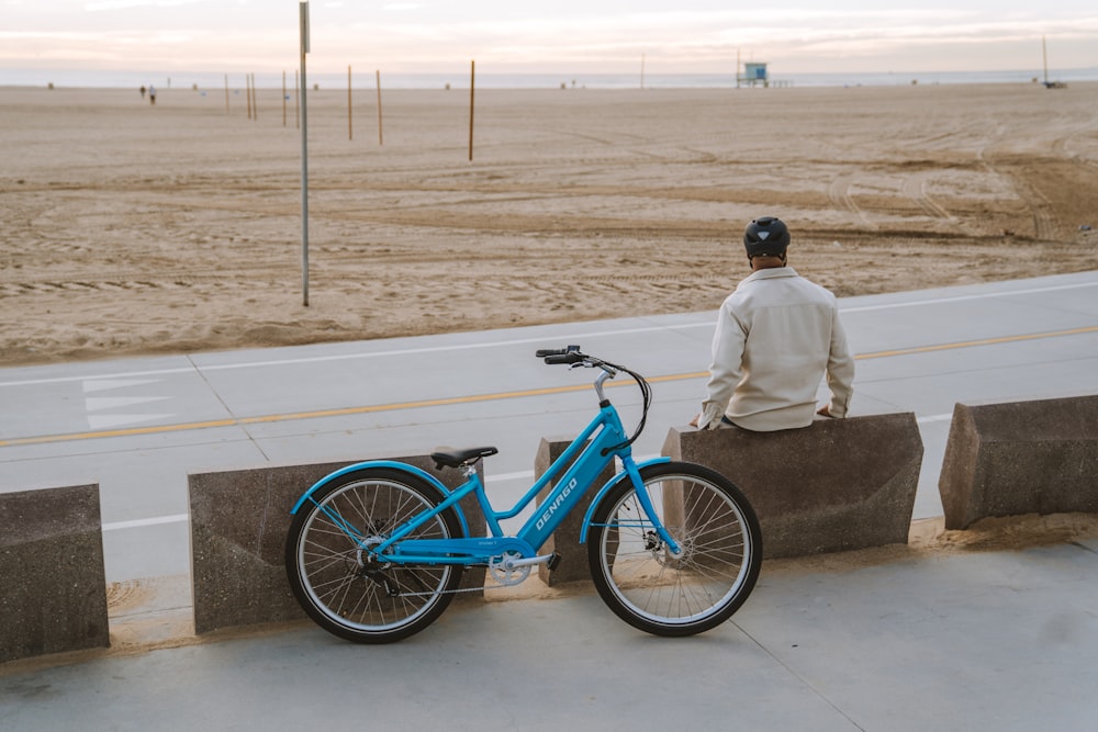a man sitting on a bench next to a blue bike