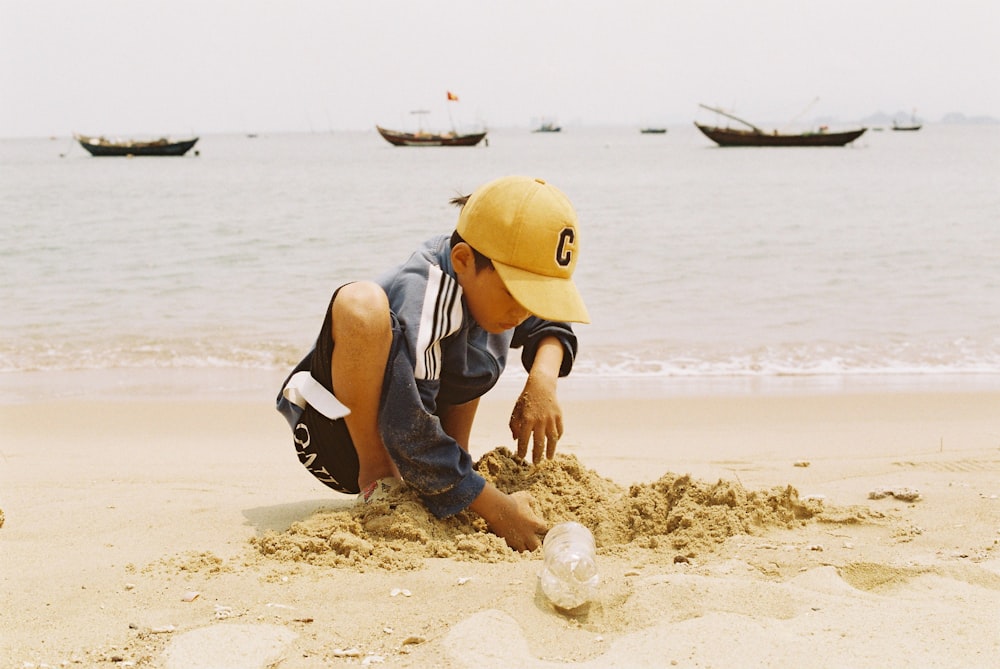 a little boy playing in the sand at the beach