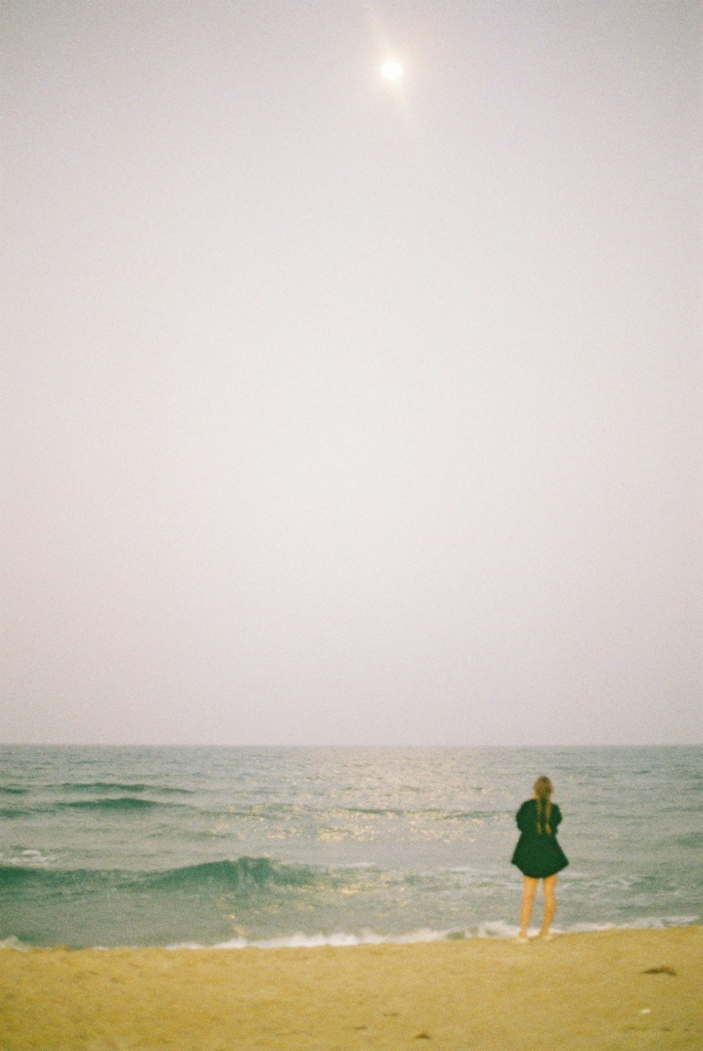 a person standing on a beach flying a kite