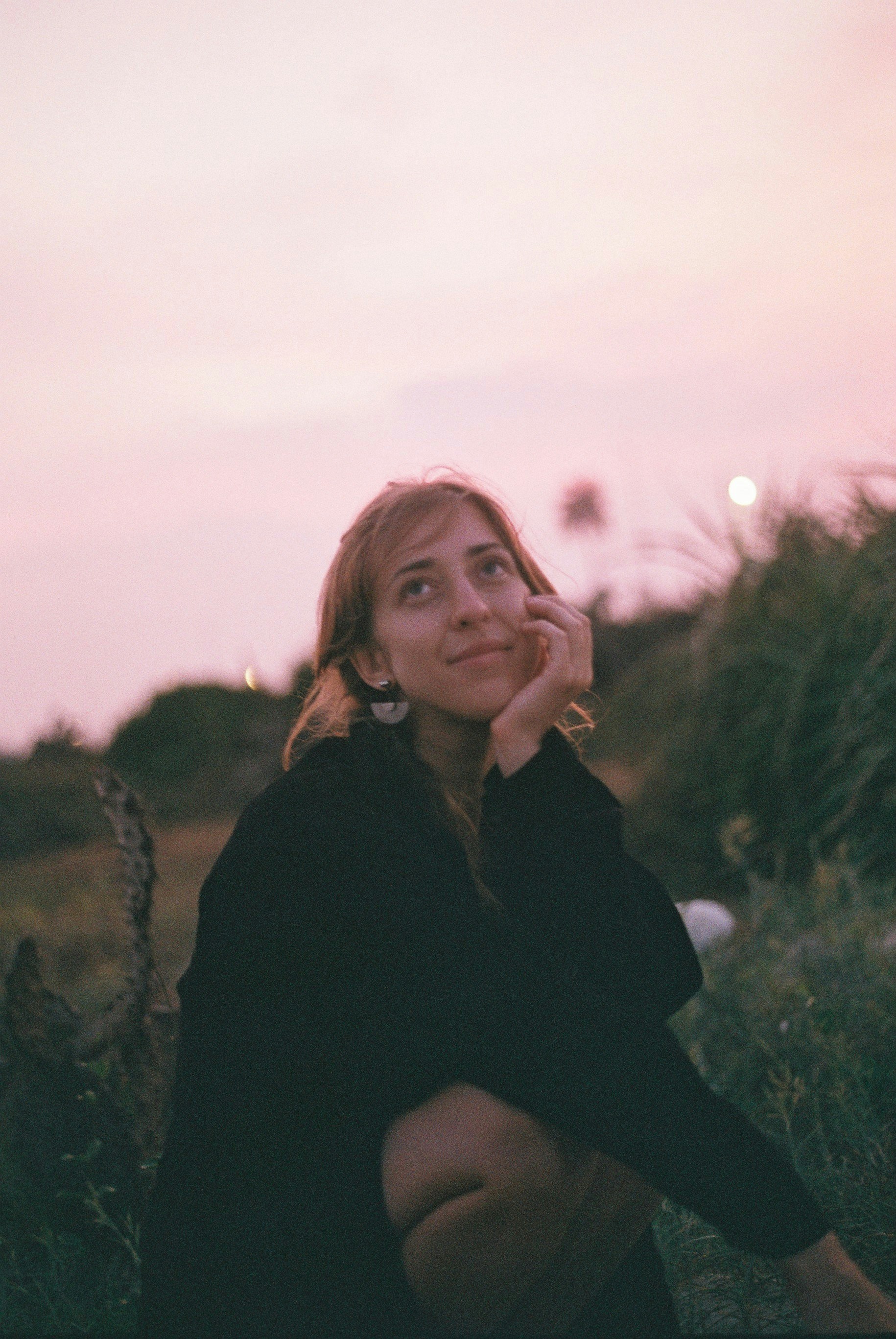 a woman sitting on the ground with her hand under her chin