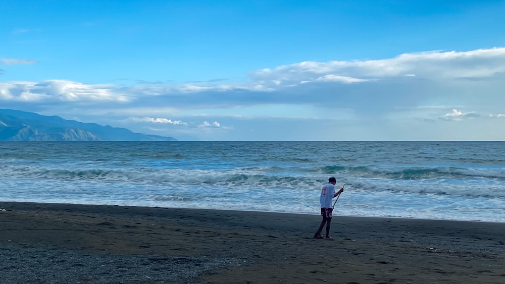 a man standing on top of a beach next to the ocean