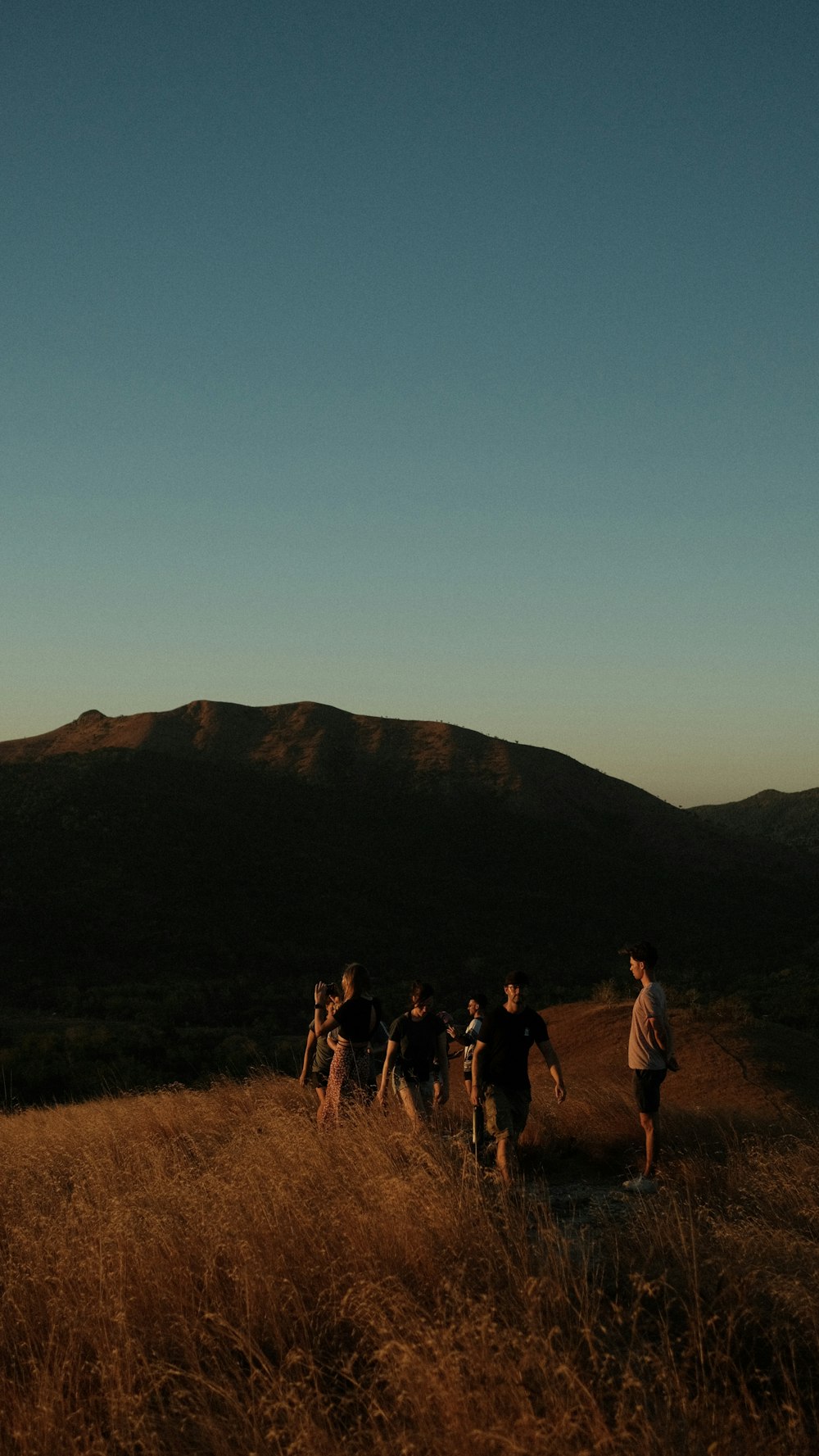 a group of people standing on top of a grass covered hillside