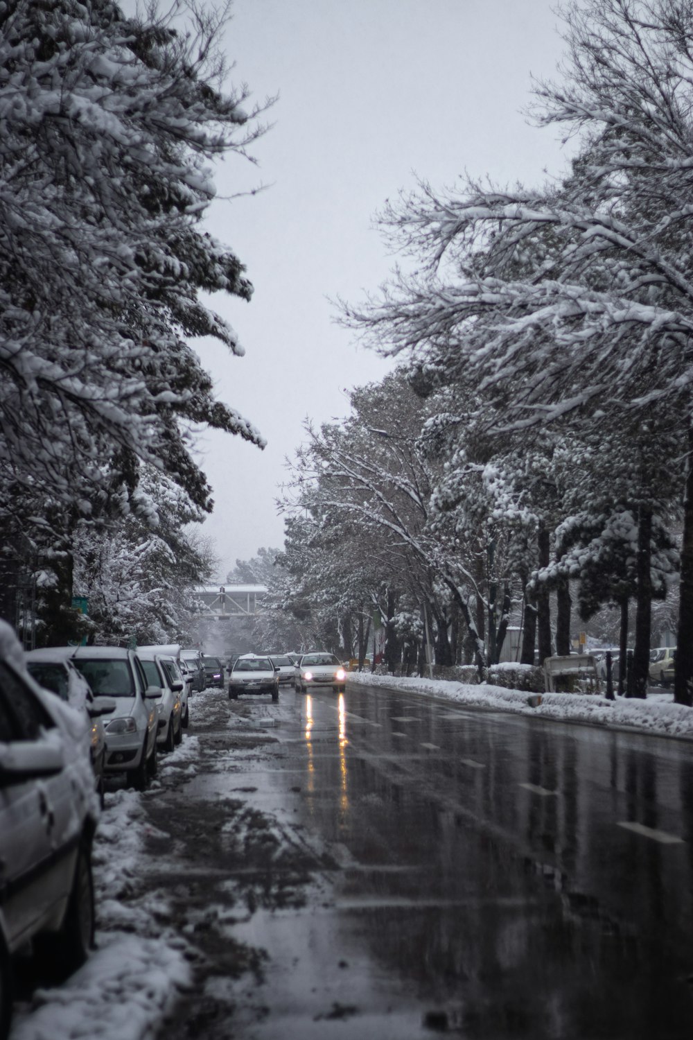 una calle nevada con coches aparcados a un lado