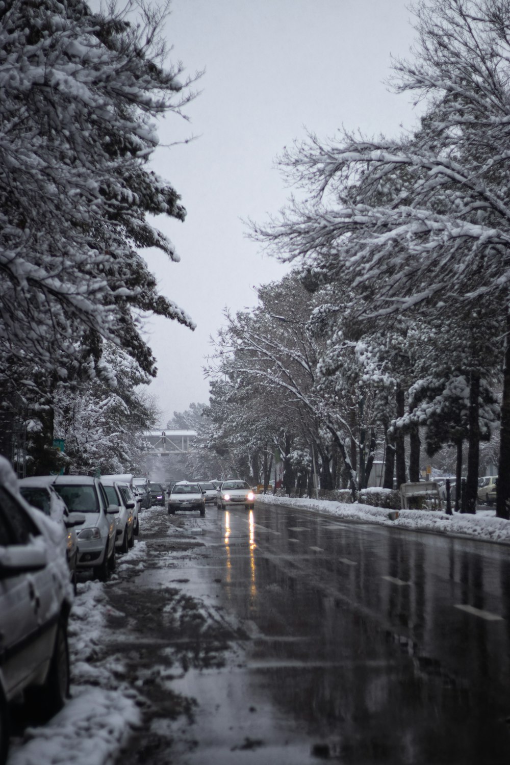 a snowy street with cars parked on the side of it