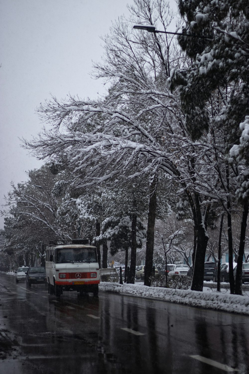 a red and white bus driving down a snow covered street