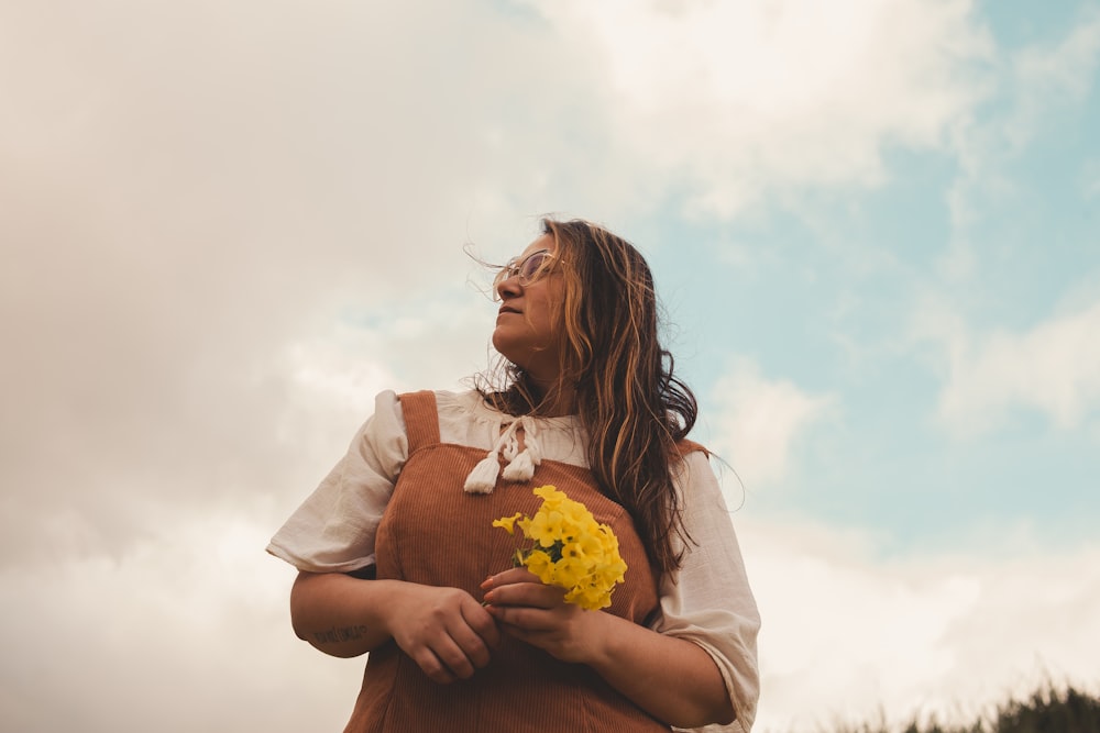 a woman holding a bunch of yellow flowers