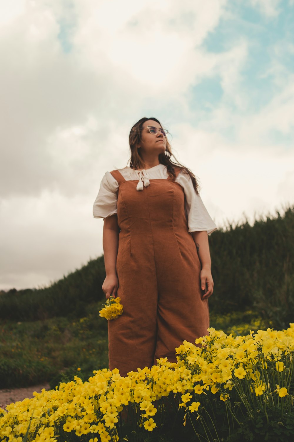 a woman standing in a field of yellow flowers