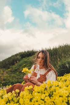 a woman sitting in a field of yellow flowers
