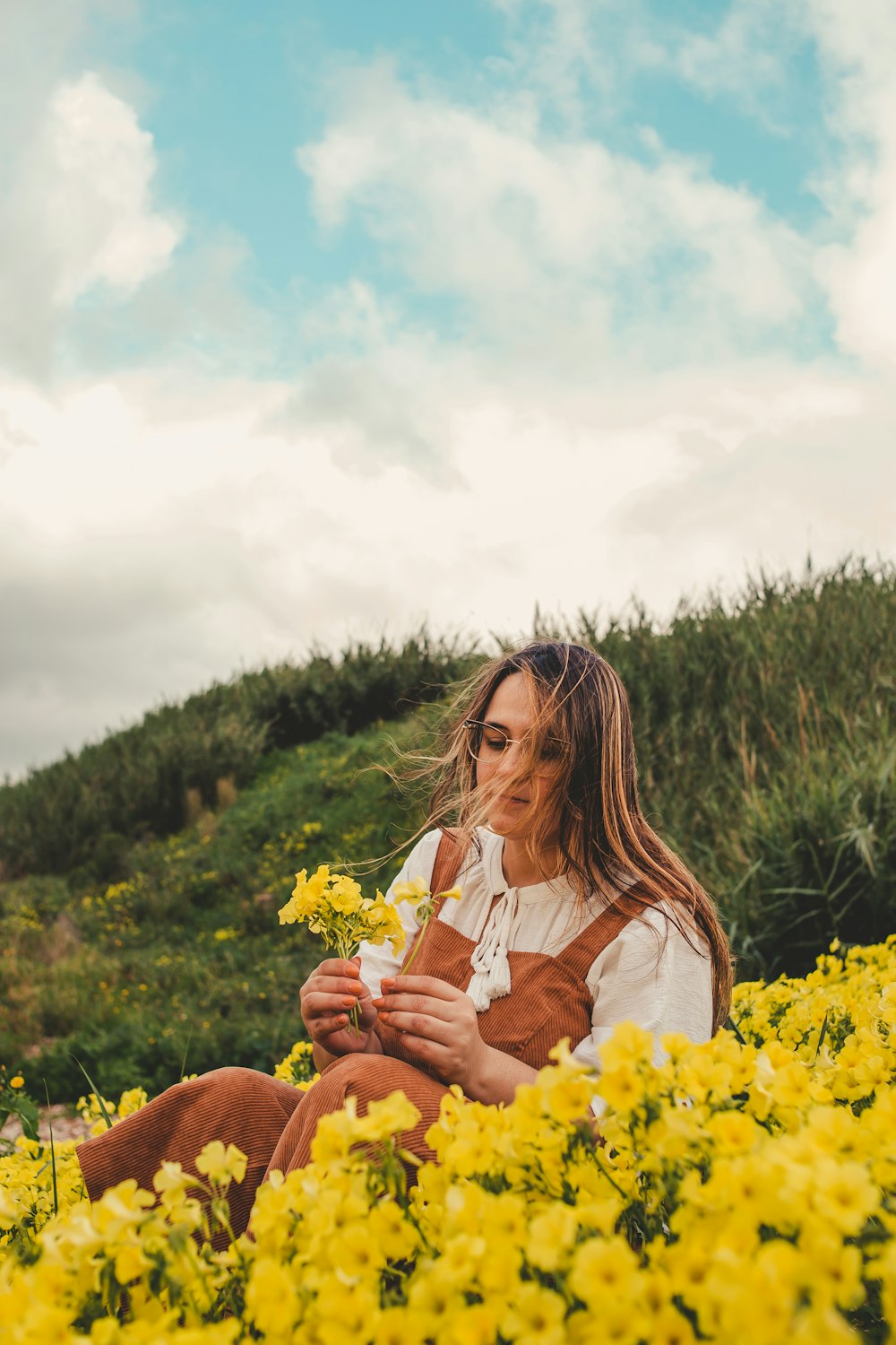 a woman sitting in a field of yellow flowers