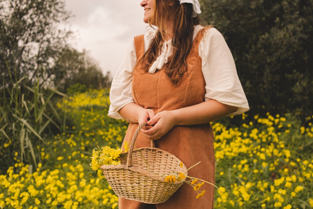 a woman standing in a field holding a basket