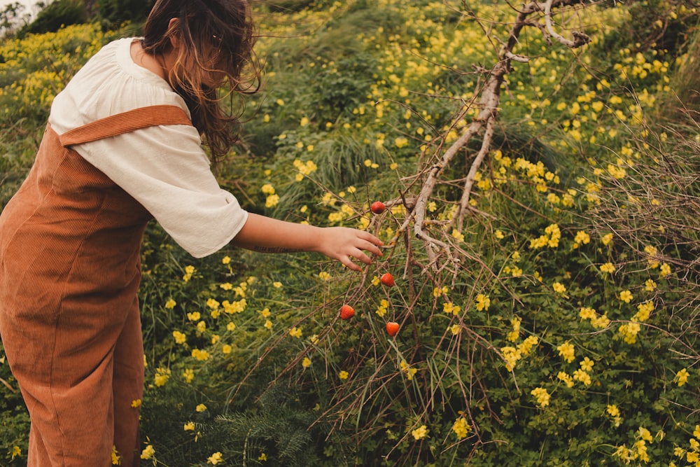 a woman picking berries off of a bush