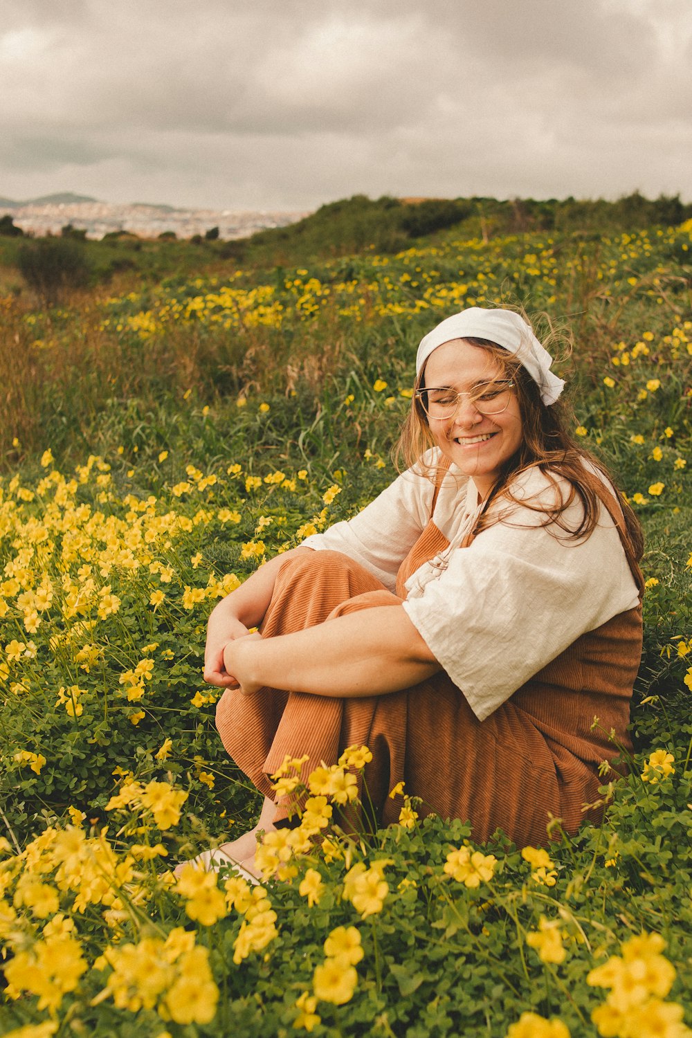 a woman sitting in a field of yellow flowers