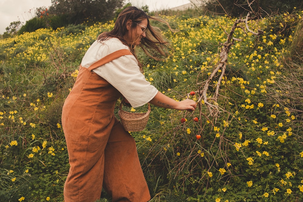 a woman picking berries from a bush in a field