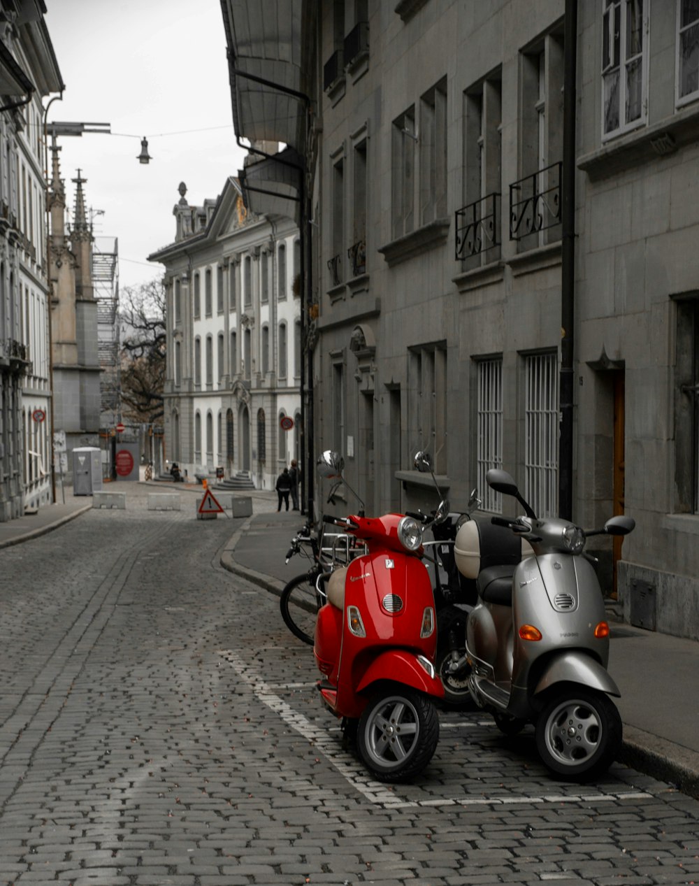 a row of scooters parked on a cobblestone street