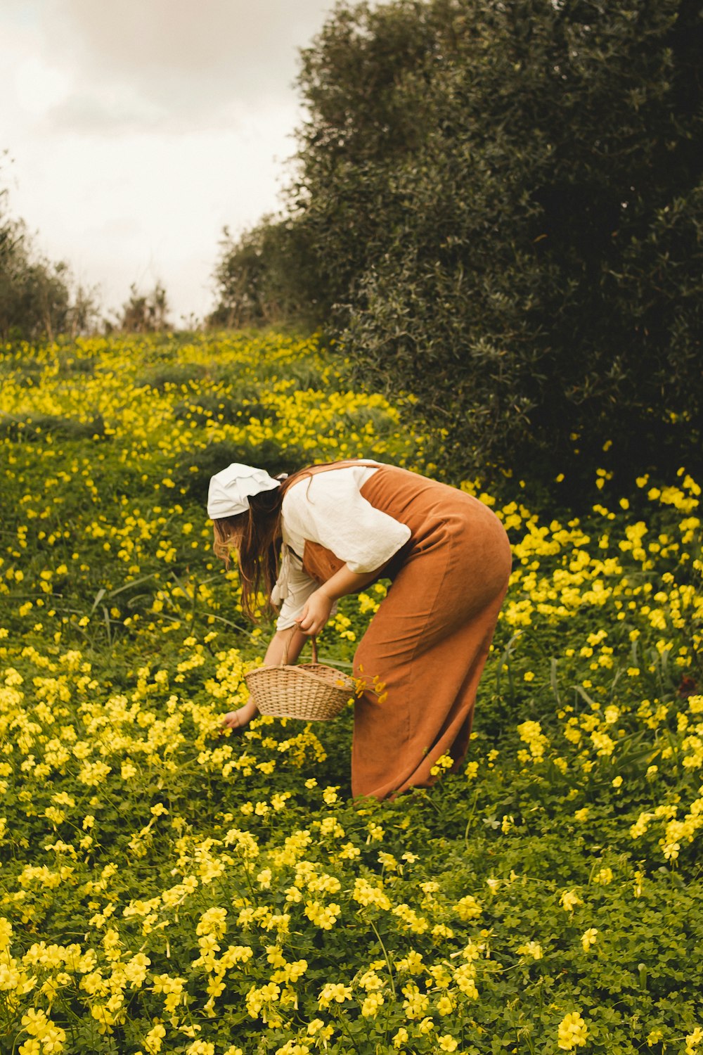 a woman kneeling down in a field of yellow flowers
