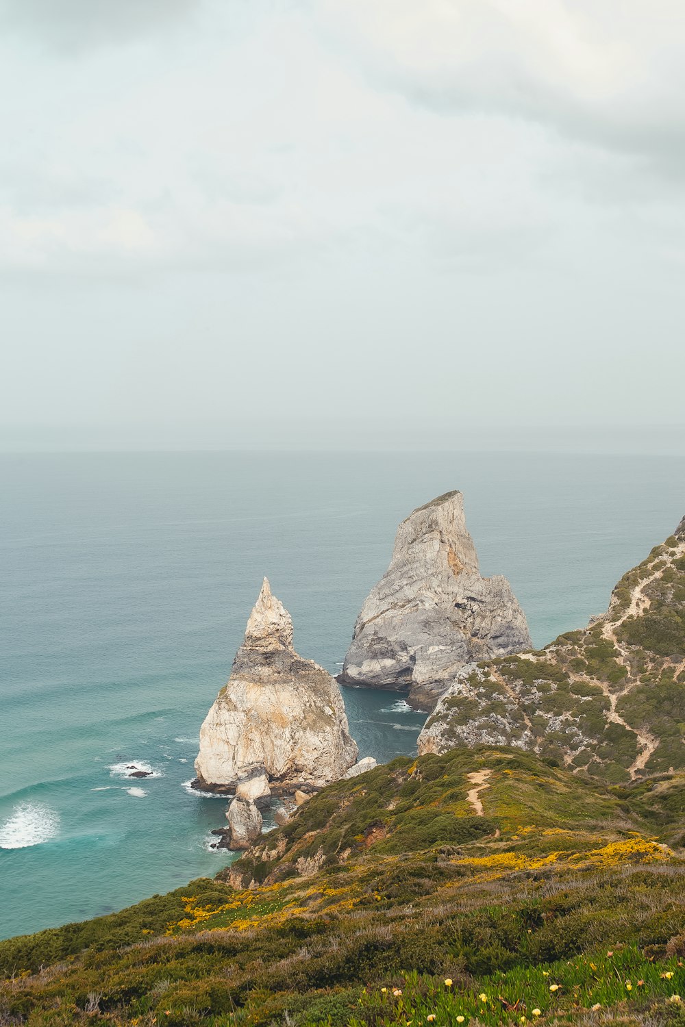 un par de grandes rocas asentadas en la cima de una exuberante ladera verde