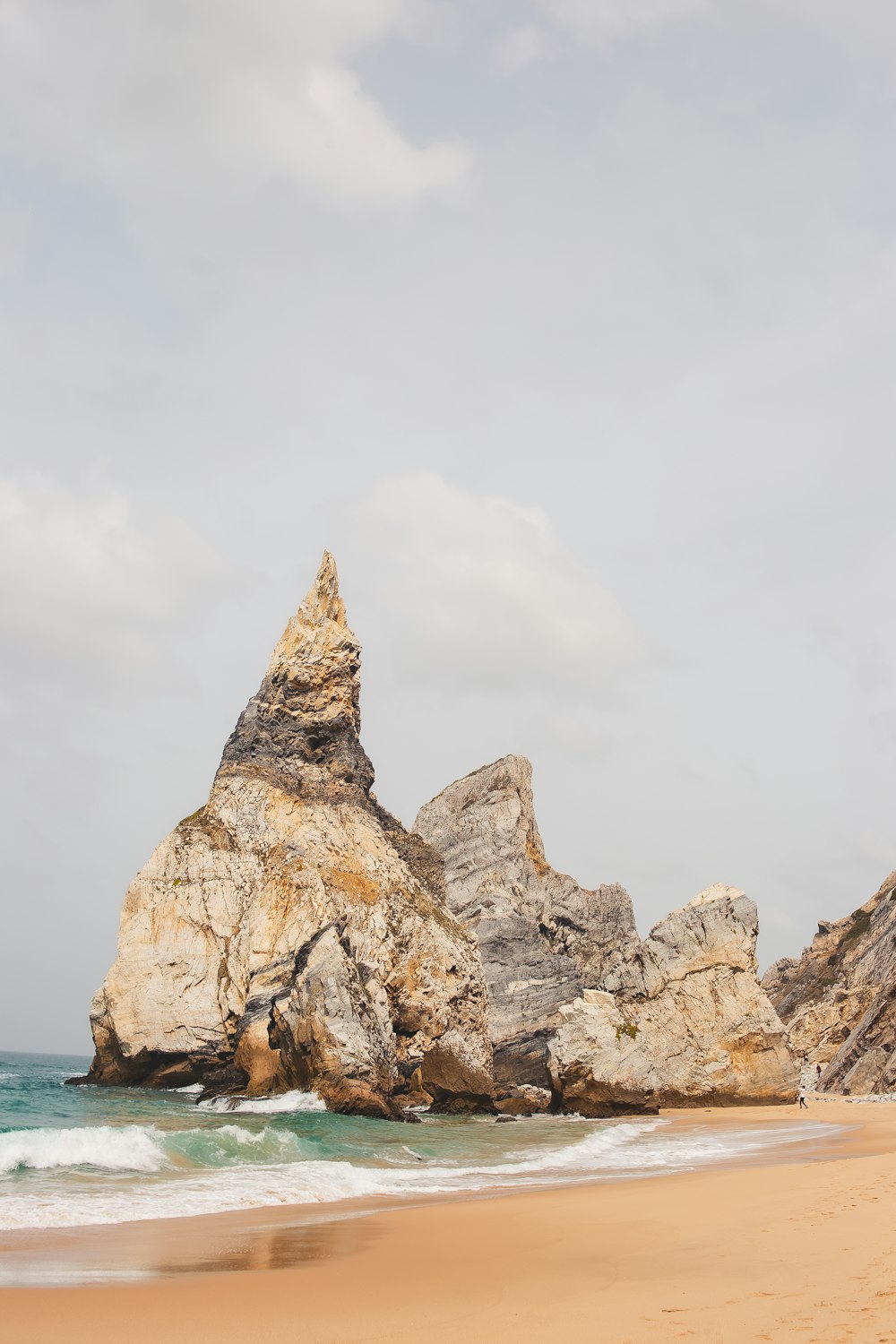 a large rock formation on the beach near the ocean