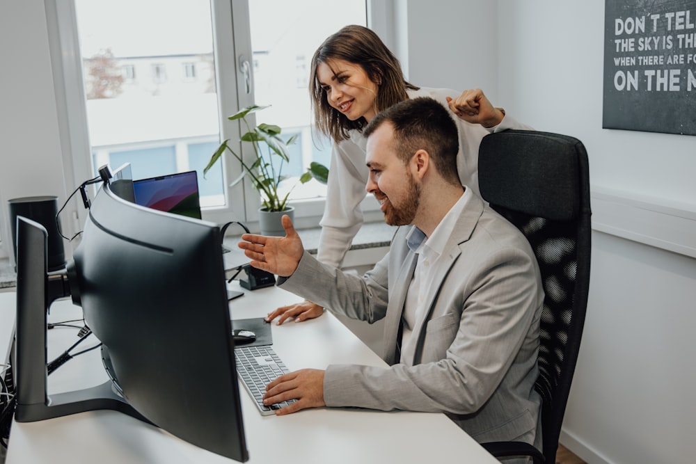 a man and woman sitting at a desk in front of a computer