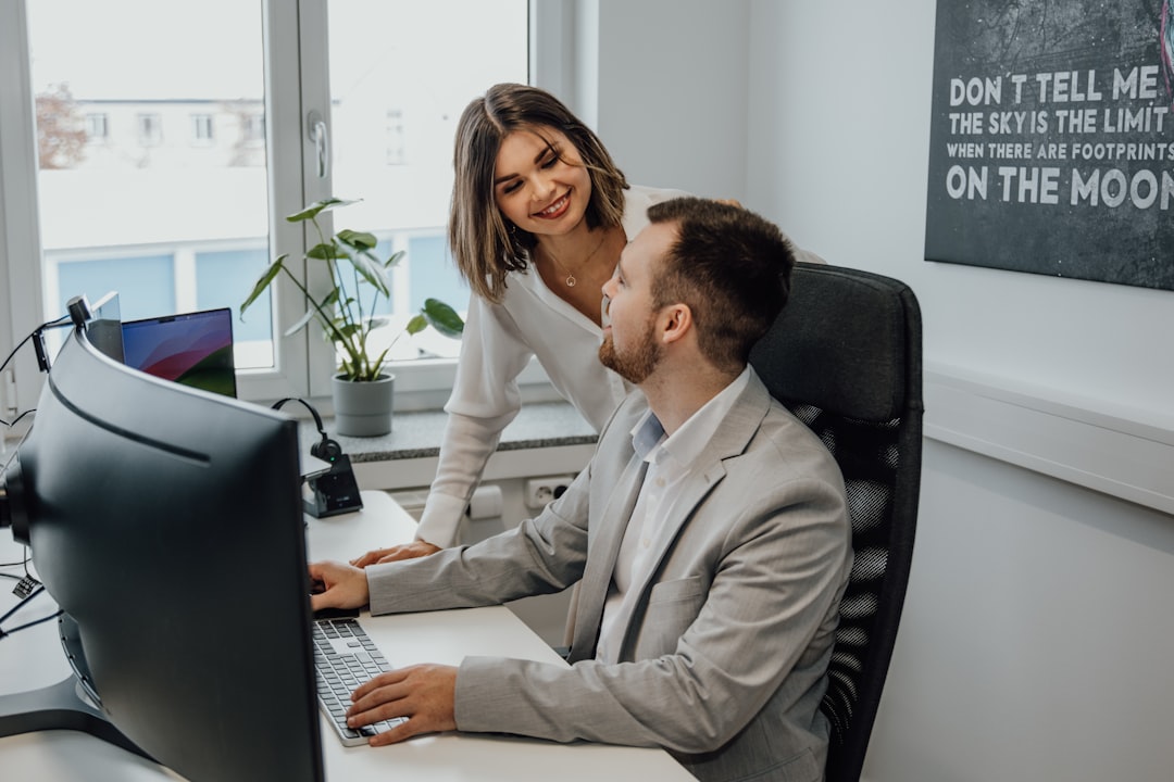 a man and a woman sitting at a desk in front of a computer,