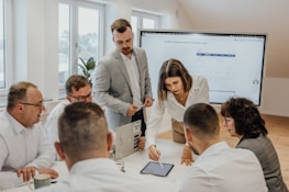 a group of people sitting around a table with laptops